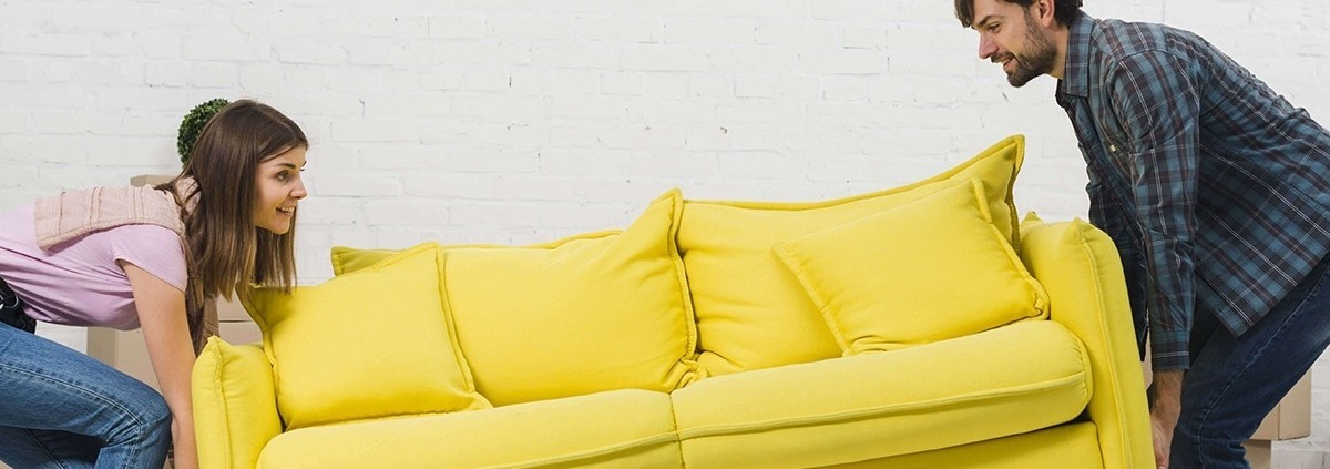 Ventajas de contratar un servicio de guardamuebles - Pareja intentando mover un sofá