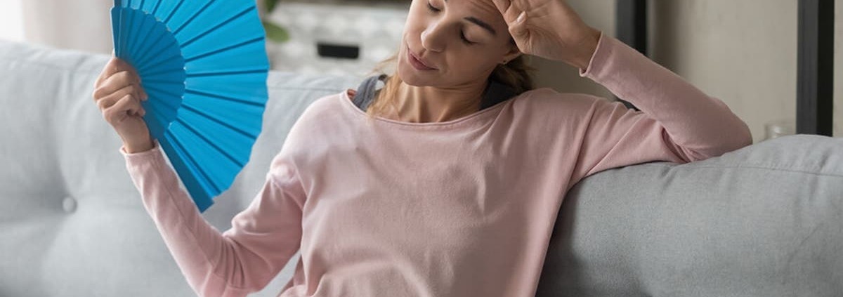 Conoce algunos trucos para pasar menos calor en casa en verano por menos precio Trucos para pasar menos calor en casa - Mujer abanicándose
