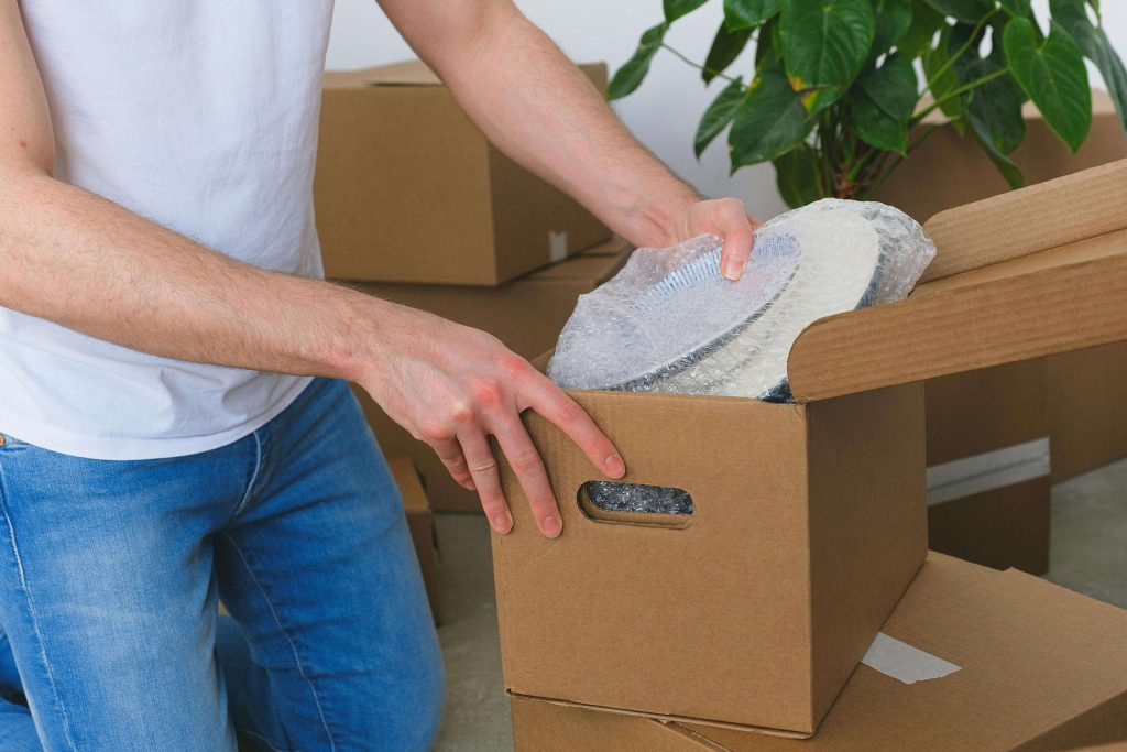 man putting dishes away in box